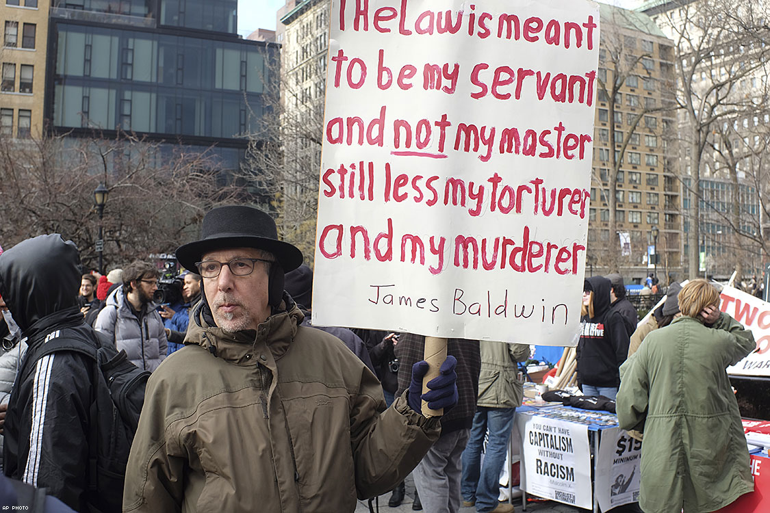 January 19, 2015: Several hundred activists gathered at Union Square Park prior to starting the Four Mile March on Martin Luther King's birthday. An activist holds a sign quoting James Baldwin.